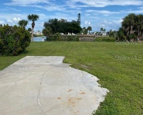 A concrete slab sits in a grassy yard overlooking a small canal and trees — 1379 FLAMINGO DRIVE, ENGLEWOOD, FL