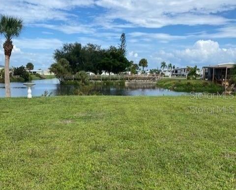 A grassy lawn overlooks a pond with a wooden bridge and distant residential structures — 1379 FLAMINGO DRIVE, ENGLEWOOD, FL