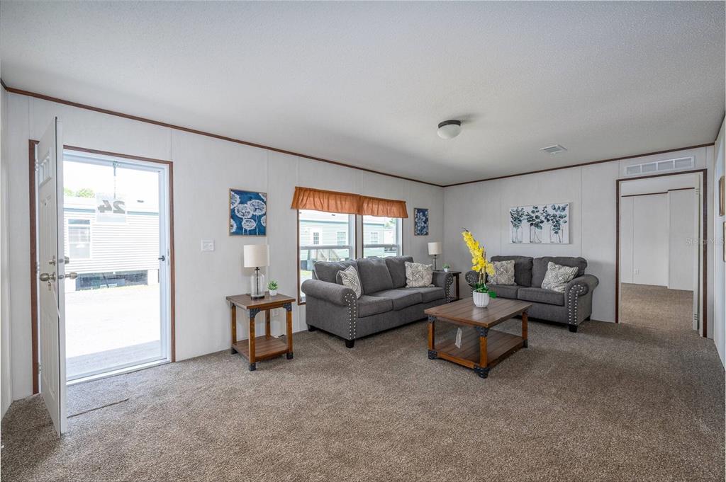A living room features gray sofas, a wooden coffee table, and beige carpeting — 1119 NE COUNTY ROAD 125, LAWTEY, FL