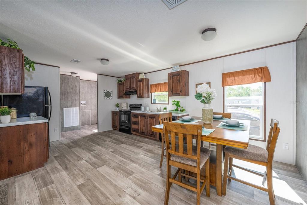 A kitchen and dining area with wood cabinets, wood-look flooring, and a wooden dining set — 1119 NE COUNTY ROAD 125, LAWTEY, FL