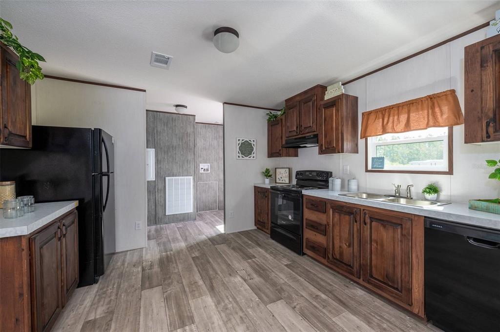 A kitchen with wood cabinets, black appliances, light countertops, and wood-look flooring — 1119 NE COUNTY ROAD 125, LAWTEY, FL