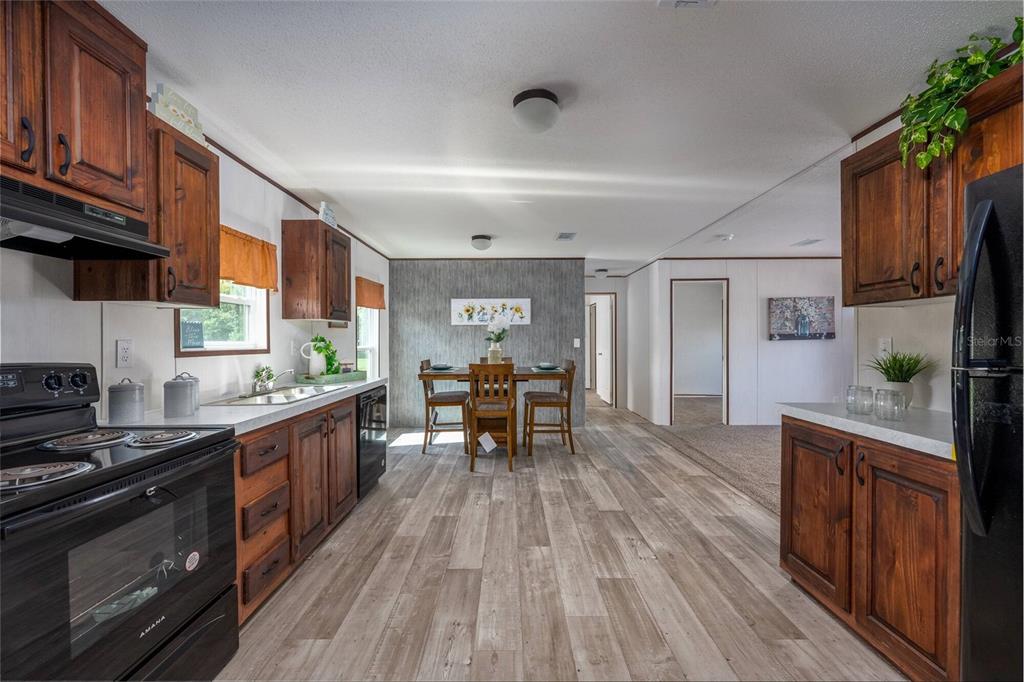 A kitchen with wood cabinets, black appliances, and a dining area with wood-look flooring — 1119 NE COUNTY ROAD 125, LAWTEY, FL