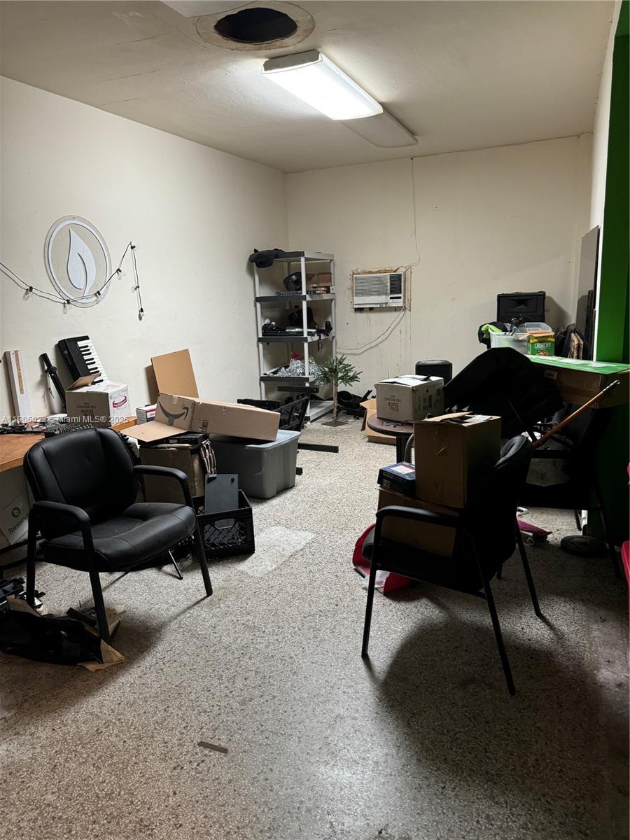 A cluttered, unfinished room with concrete floors, a window air conditioner, and overhead lighting — 12495 NE 2nd Ave, North Miami FL 33161, NORTH MIAMI, FL