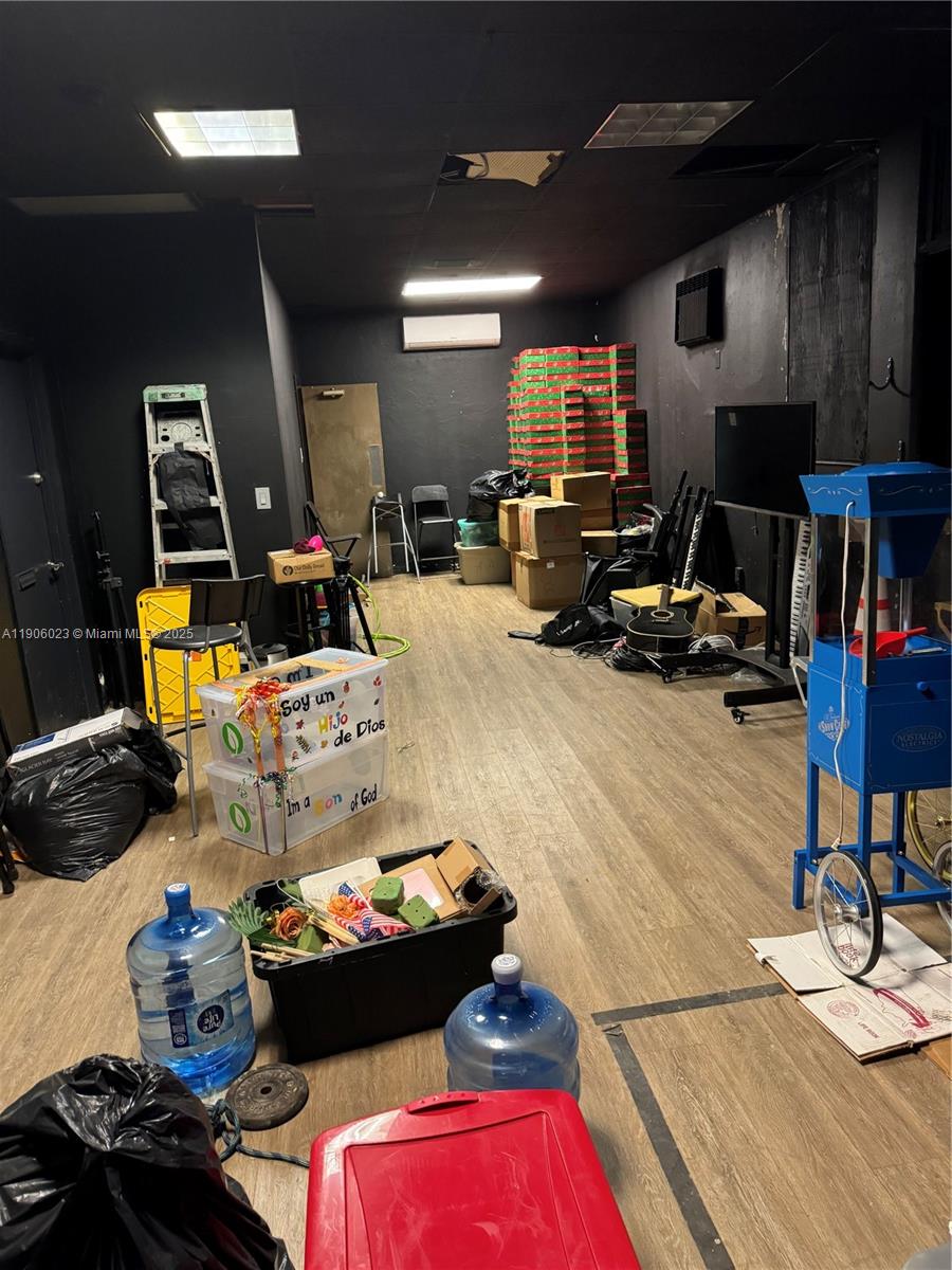 A cluttered room with black walls, wood-look flooring, and various storage boxes and equipment — 12495 NE 2nd Ave, North Miami FL 33161, NORTH MIAMI, FL