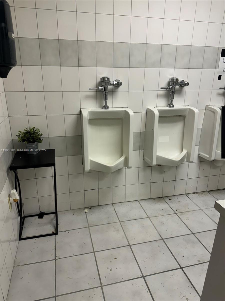 A public restroom features white tiled walls and two wall-mounted urinals — 12495 NE 2nd Ave, North Miami FL 33161, NORTH MIAMI, FL