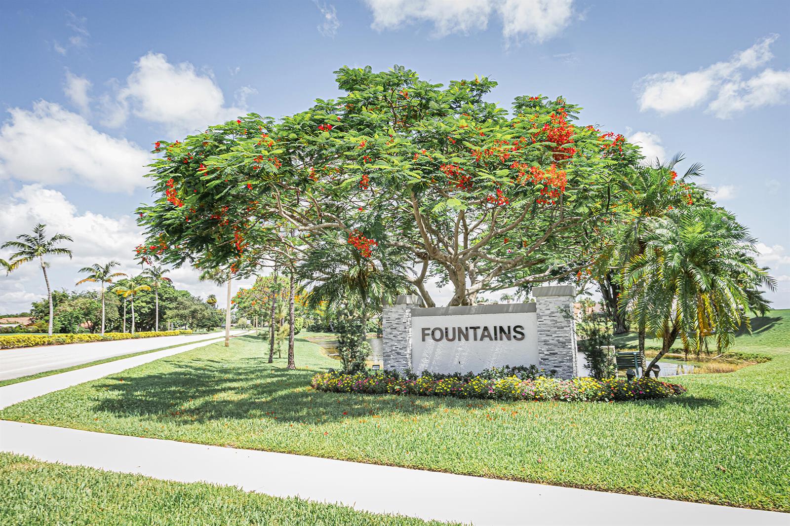A stone monument sign labeled Fountains sits beneath a large flowering tree on a lawn — 5148 Rosen Boulevard, Boynton Beach FL 33472, BOYNTON BEACH, FL