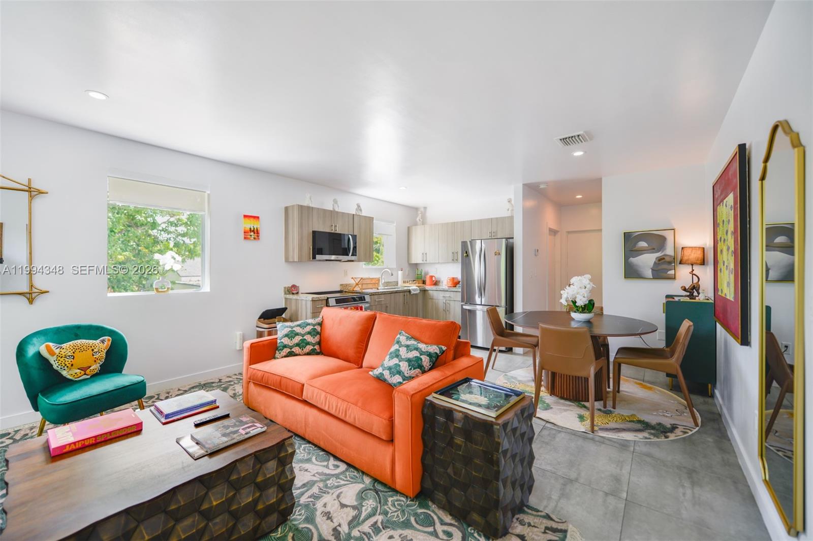 An open-concept living and dining area features an orange sofa, green armchair, and kitchen — 165 NW 39th St # 7, Miami FL 33127, MIAMI, FL