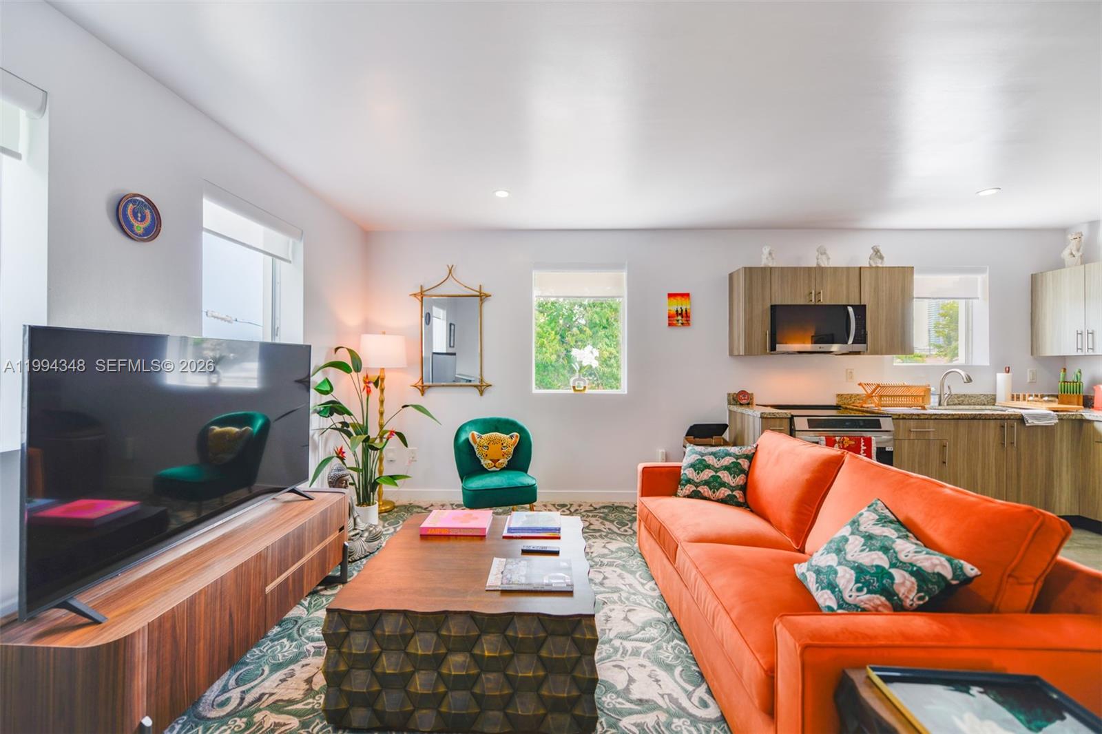 A living room features an orange sofa, a patterned rug, and an open kitchen area — 165 NW 39th St # 7, Miami FL 33127, MIAMI, FL