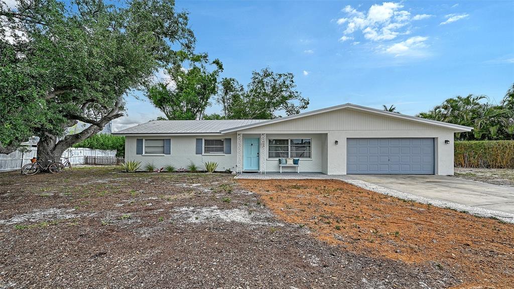 A single-story house with a light-colored brick exterior, a gray garage door, and a blue door — 2103 LUSITANIA DRIVE, SARASOTA, FL