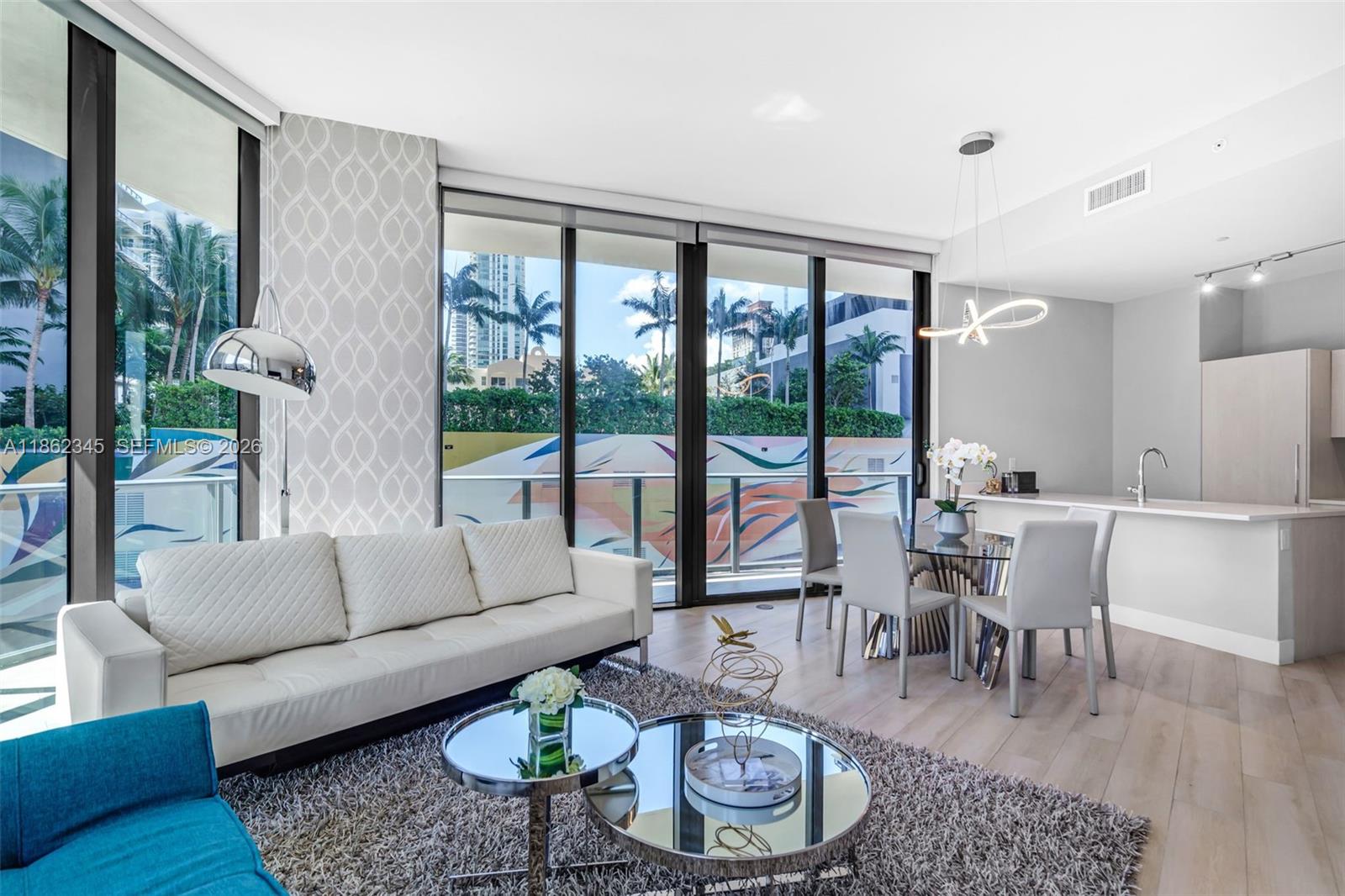 A modern living and dining area with floor-to-ceiling windows, light wood floors, and contemporary furniture — 501 NE 31st St # 306, Miami FL 33137, MIAMI, FL