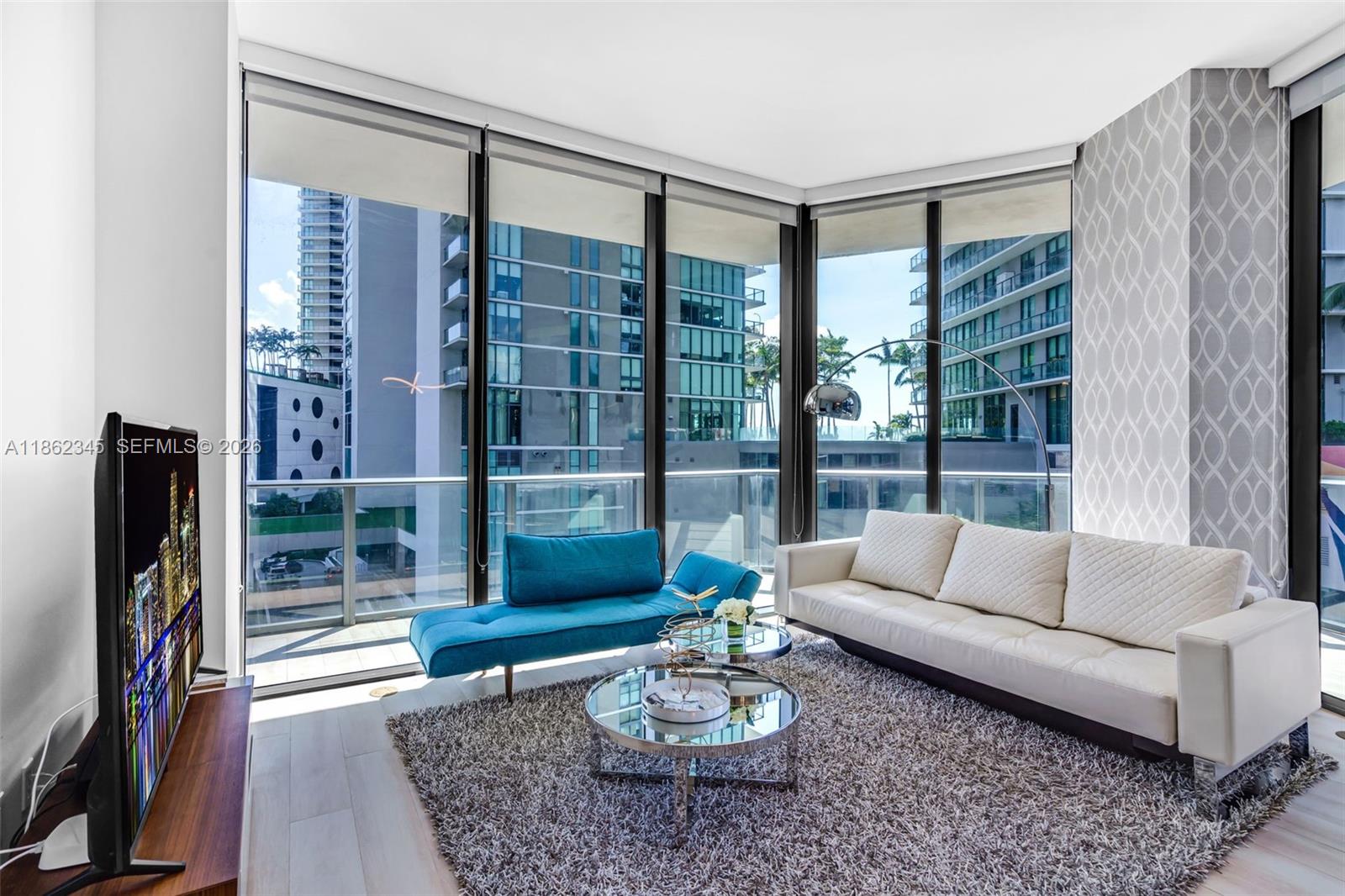 A modern living and dining area features a white sofa, glass tables, and floor-to-ceiling windows — 501 NE 31st St # 306, Miami FL 33137, MIAMI, FL