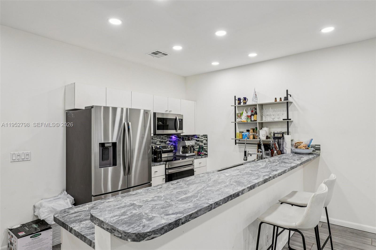 A kitchen features white cabinets, stainless steel appliances, and a gray marble-patterned breakfast bar — 2307 Washington St # 5, Hollywood FL 33020, HOLLYWOOD, FL