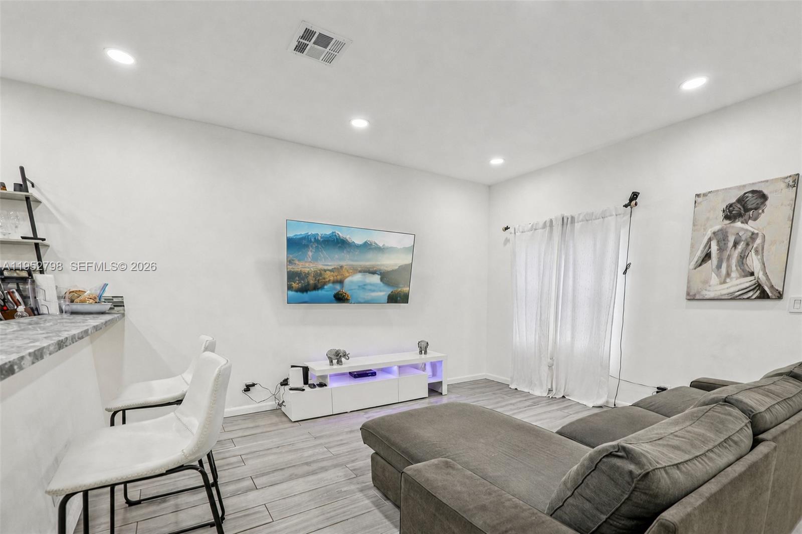 A living room features a wall-mounted television, a white media console, and a grey sectional — 2307 Washington St # 5, Hollywood FL 33020, HOLLYWOOD, FL