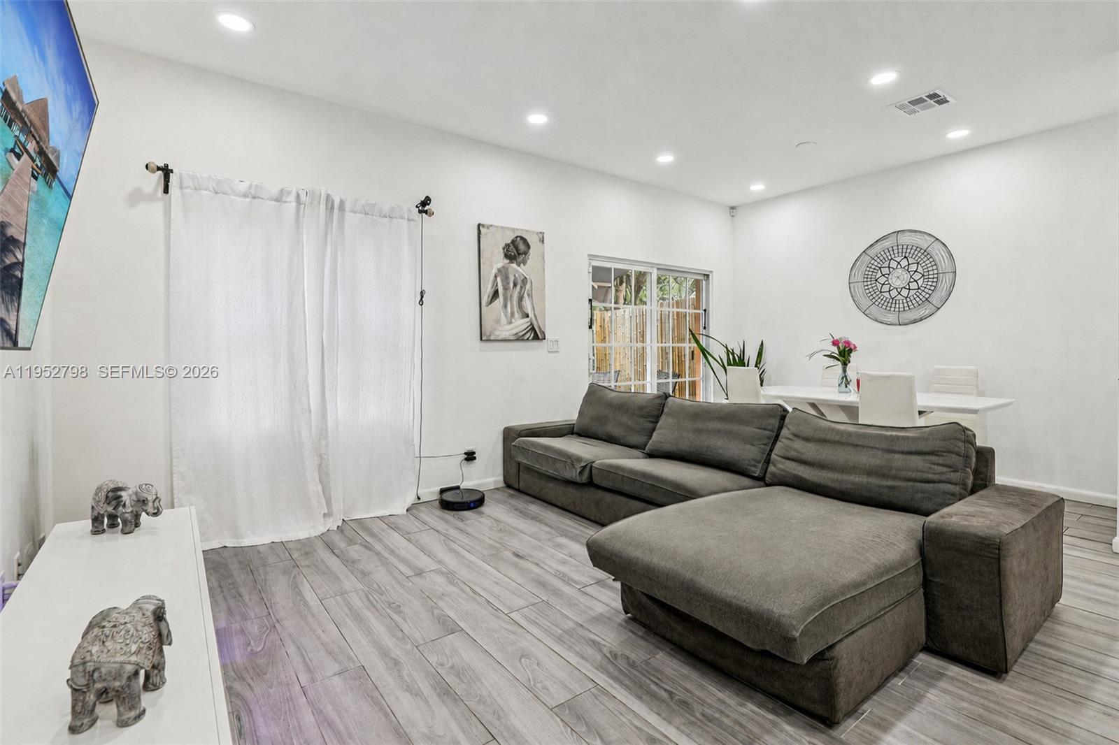A living room features a grey sectional sofa, white walls, and wood-look tile flooring — 2307 Washington St # 5, Hollywood FL 33020, HOLLYWOOD, FL