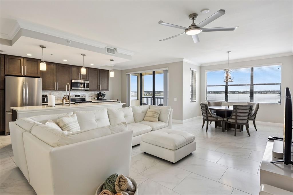 An open-concept living and dining area features white tile floors, a sectional sofa, and kitchen — 16300 COUNTY ROAD 455 UNIT 302, MONTVERDE, FL
