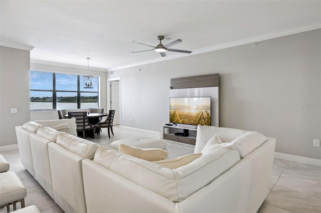 A living room features a white sectional sofa, a television on a wall-mounted unit, and a dining area — 16300 COUNTY ROAD 455 UNIT 302, MONTVERDE, FL