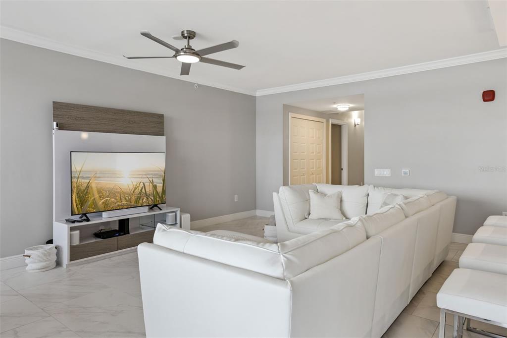 A living room features a white sectional sofa, a wall-mounted television, and tile flooring — 16300 COUNTY ROAD 455 UNIT 302, MONTVERDE, FL