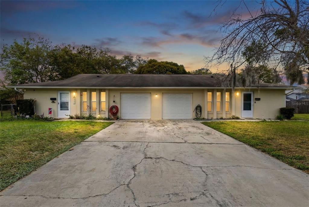 A single-story duplex with two garage doors and a shared concrete driveway at dusk — 6602 POT O GOLD LANE, ORLANDO, FL