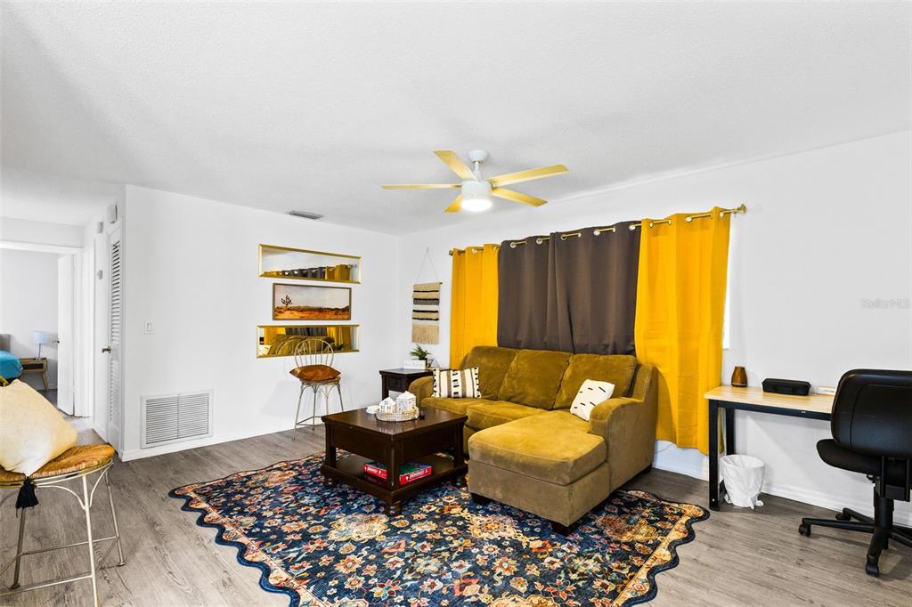 A living room features a yellow sectional sofa, a patterned rug, and a ceiling fan — 6602 POT O GOLD LANE, ORLANDO, FL