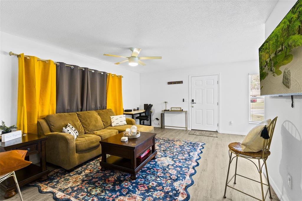 A living room features a brown sectional sofa, a patterned area rug, and a ceiling fan — 6602 POT O GOLD LANE, ORLANDO, FL