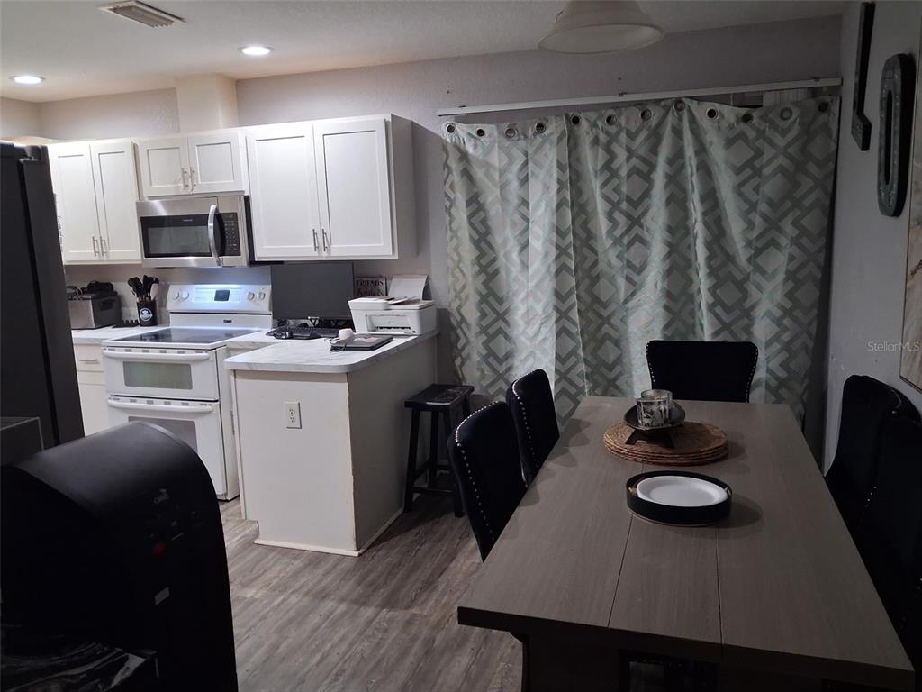 A kitchen with white cabinets and a dining area featuring a table and chairs — 505 HOLT CIRCLE, WINTER HAVEN, FL