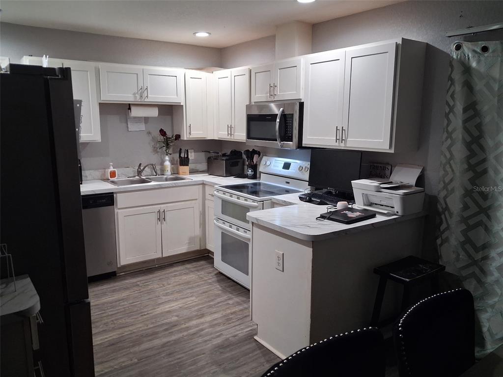 A kitchen features white cabinets, stainless steel appliances, and a small desk area with a printer — 505 HOLT CIRCLE, WINTER HAVEN, FL