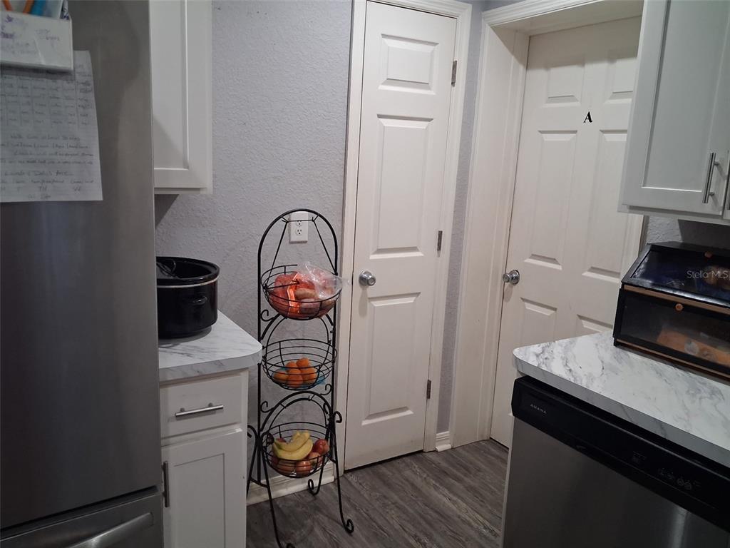 A kitchen features white cabinets, stainless steel appliances, a wire produce rack, and two doors — 505 HOLT CIRCLE, WINTER HAVEN, FL