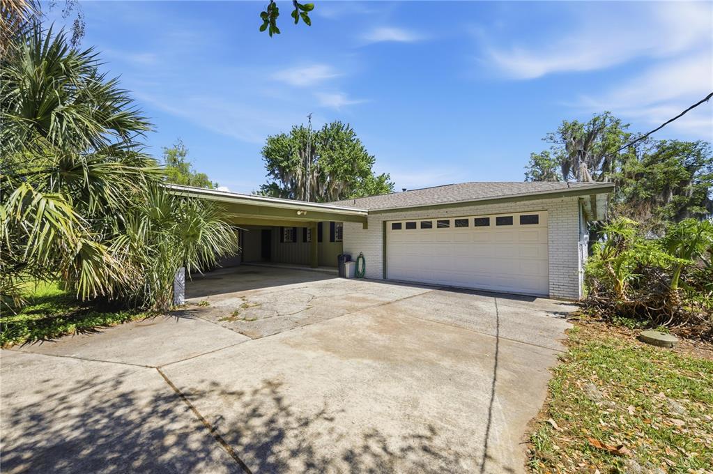 A single-story house with a white brick exterior, a two-car garage, and a carport — 21407 NW 39TH COURT, MICANOPY, FL