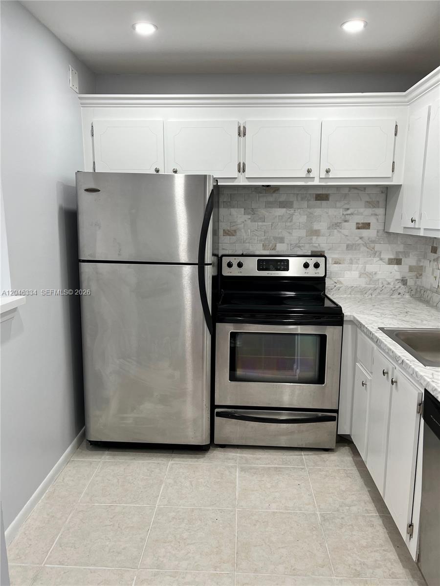 A kitchen features stainless steel appliances, white cabinets, and a marble-patterned backsplash and countertop — 359 Preston I # I, Boca Raton FL 33434, BOCA RATON, FL