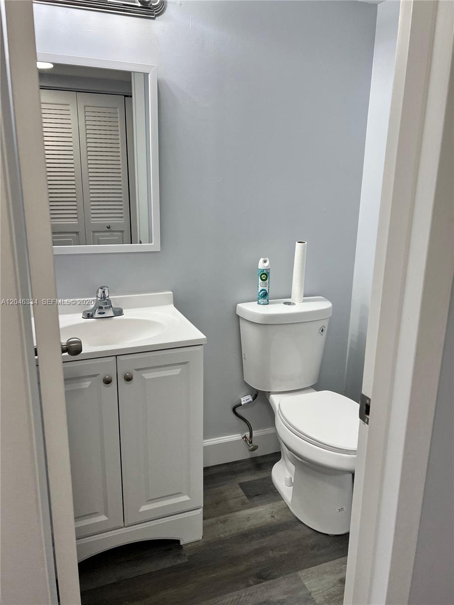 A small bathroom features a white vanity, a toilet, and gray wood-look flooring — 359 Preston I # I, Boca Raton FL 33434, BOCA RATON, FL