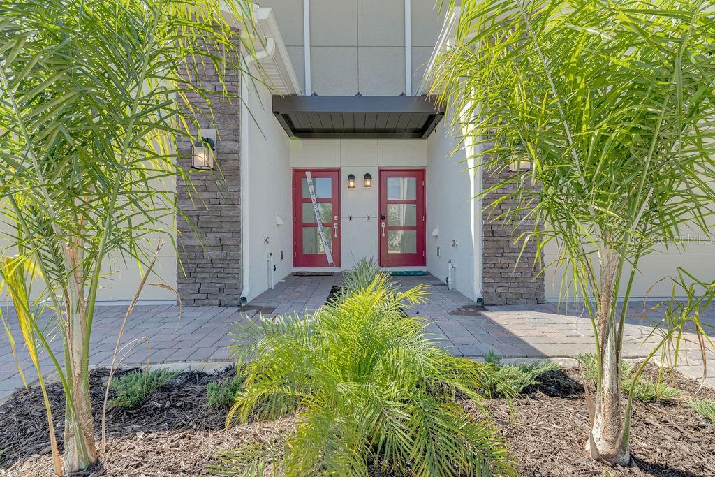 The exterior entrance features two red front doors flanked by stone pillars and palm trees — 9327 SOMMERSET HILLS DRIVE UNIT 9327, DAVENPORT, FL