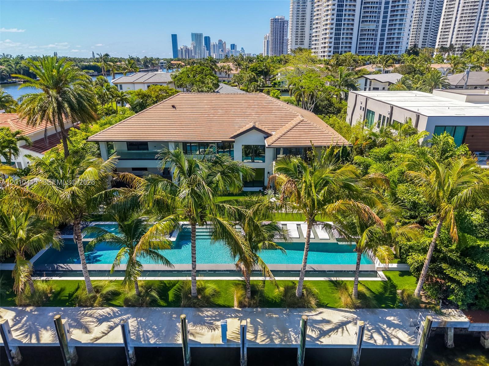 An aerial view shows a waterfront house with a swimming pool, palm trees, and dock — 110 Holiday Dr, Hallandale Beach FL 33009, HALLANDALE BEACH, FL