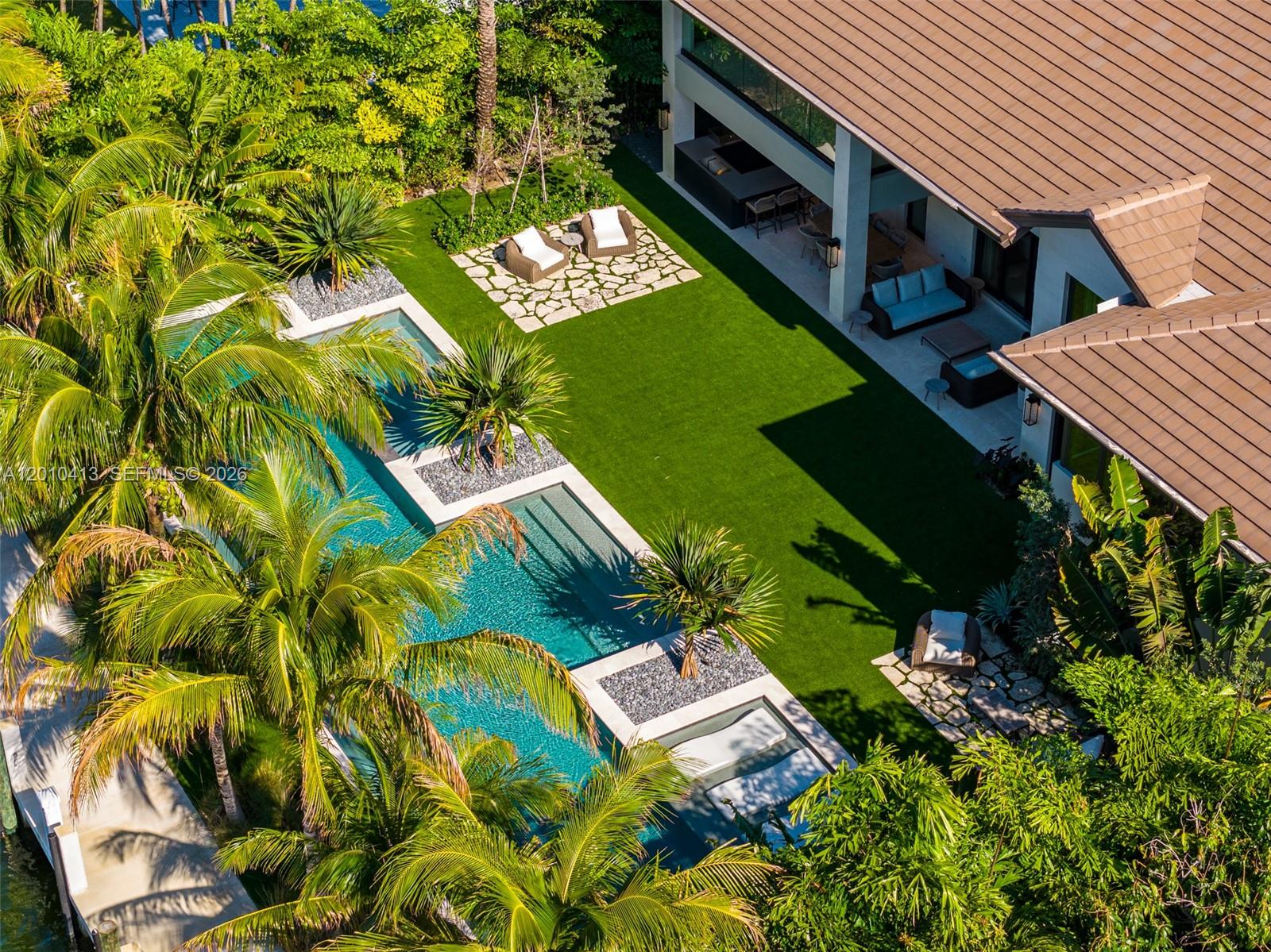 An aerial view shows a backyard with a swimming pool, artificial turf, and patio furniture — 110 Holiday Dr, Hallandale Beach FL 33009, HALLANDALE BEACH, FL
