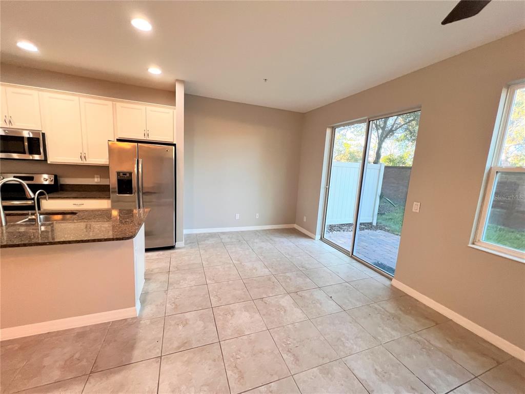 A kitchen with stainless steel appliances and tile flooring opens to a patio through sliders — 1123 PALMA VERDE PLACE, APOPKA, FL