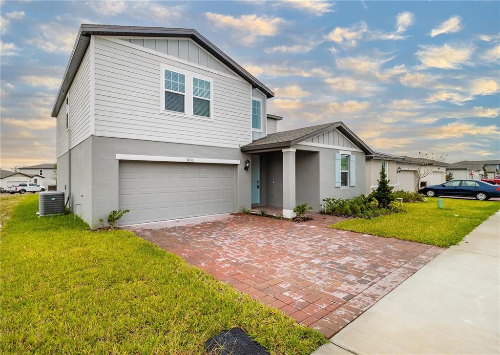 A two-story suburban house features a brick driveway, a garage, and a covered entryway — 3033 CASSIDY LANE, HAINES CITY, FL