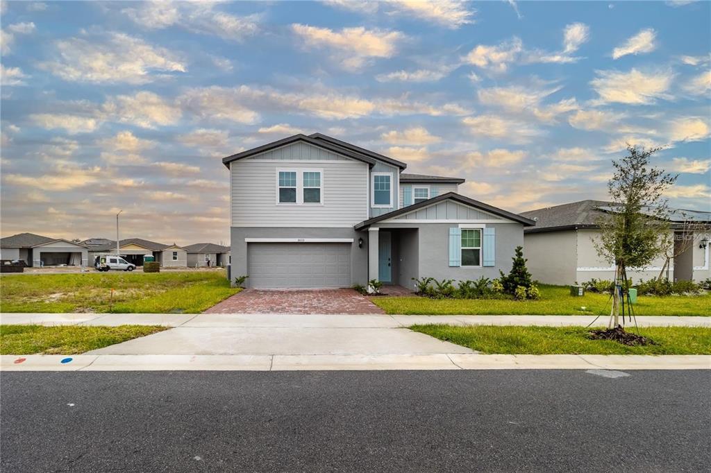 A two-story suburban house with a gray garage, light blue door, and a brick driveway — 3033 CASSIDY LANE, HAINES CITY, FL