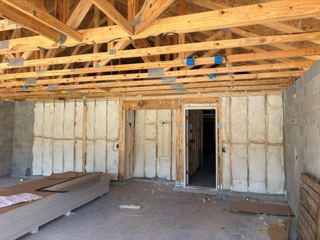 An unfinished room under construction features exposed wooden roof trusses and insulated wall studs — 17889 SW 61ST LANE ROAD, DUNNELLON, FL
