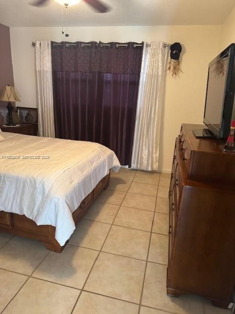 A bedroom features a bed with a white comforter, a wooden dresser, and dark curtains — 4299 NW 16th St # 103, Lauderhill FL 33313, LAUDERHILL, FL