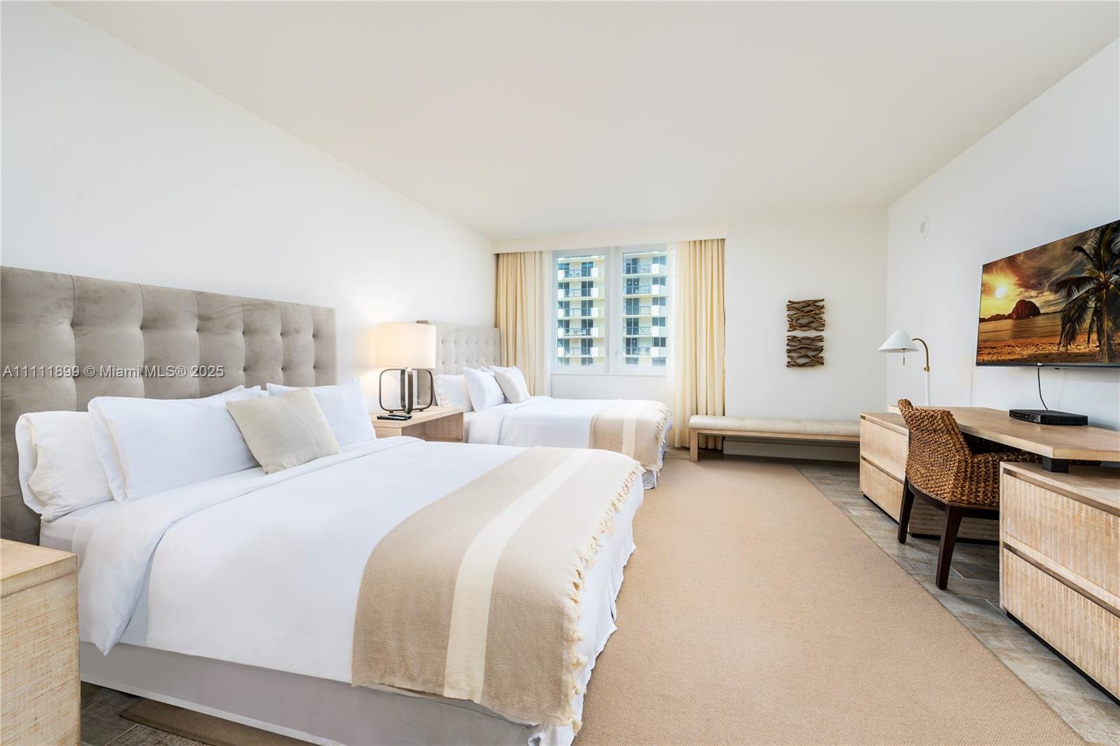 A hotel-style bedroom features two queen beds, a desk, and a wall-mounted television — 102 24th St # 1015, Miami Beach FL 33139, MIAMI BEACH, FL