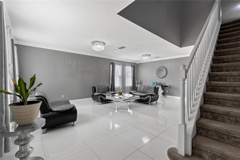 A living room features white tile floors, gray walls, modern furniture, and a carpeted staircase — 963 SPRINGS LANDING DRIVE, DELTONA, FL