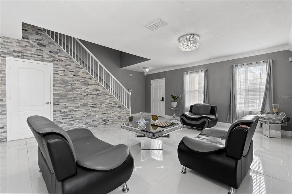 A living room features white tile floors, a stone accent wall, and modern black furniture — 963 SPRINGS LANDING DRIVE, DELTONA, FL