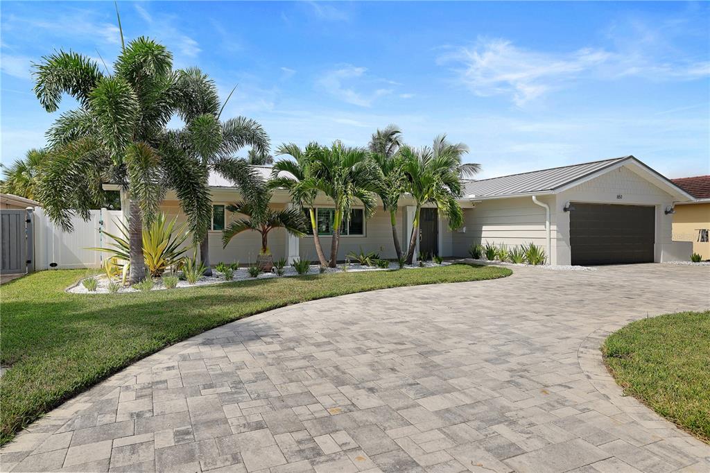 A single-story house with a paved driveway, palm trees, and a dark garage door — 651 64TH AVENUE, ST PETE BEACH, FL
