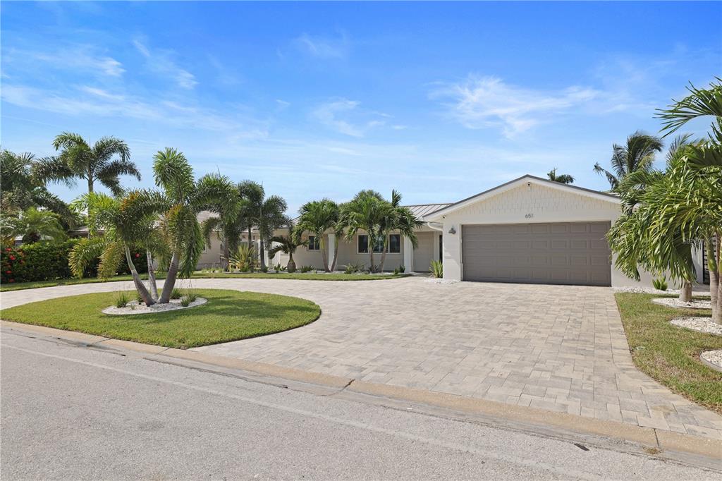 A single-story house with a paved driveway, a two-car garage, and several palm trees — 651 64TH AVENUE, ST PETE BEACH, FL