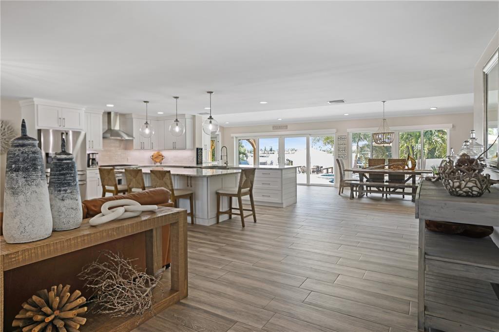 An open-concept kitchen and dining area features white cabinetry, a large island, and tile flooring — 651 64TH AVENUE, ST PETE BEACH, FL