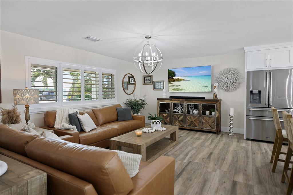 A living room features a brown leather sofa, wood coffee table, and a wall-mounted television — 651 64TH AVENUE, ST PETE BEACH, FL