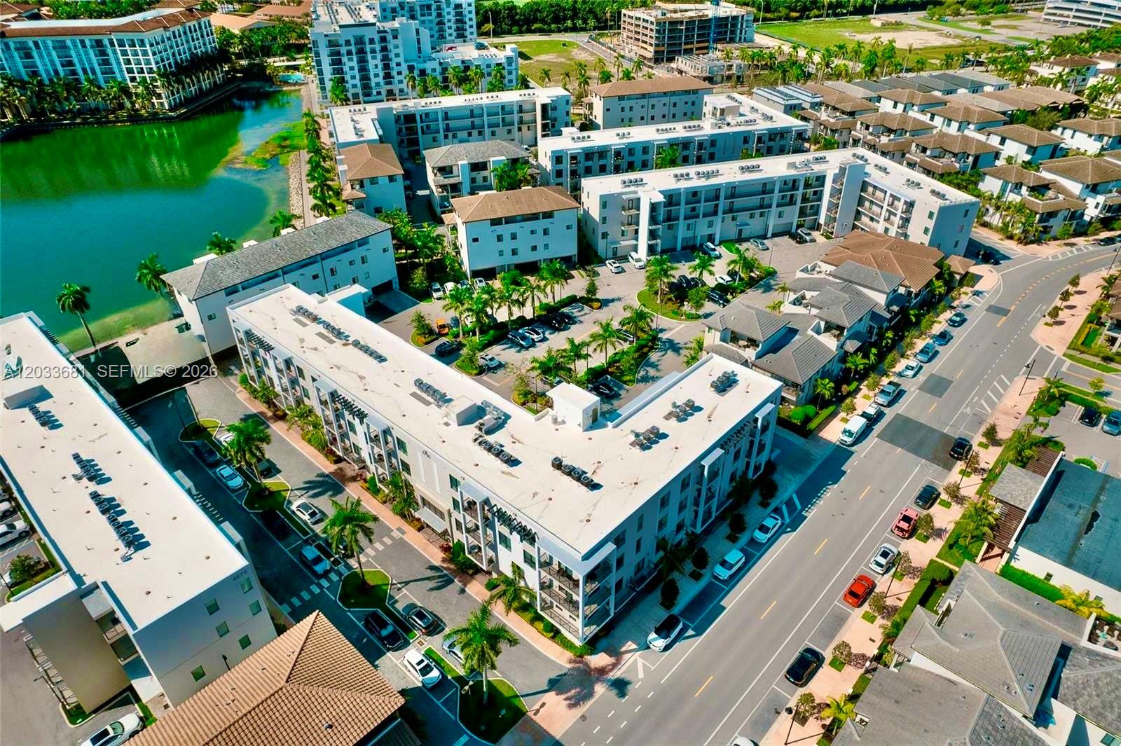An aerial view shows a multi-story apartment complex with a lake and parking lots — 4700 NW 84th Ave # 15, Doral FL 33166, DORAL, FL