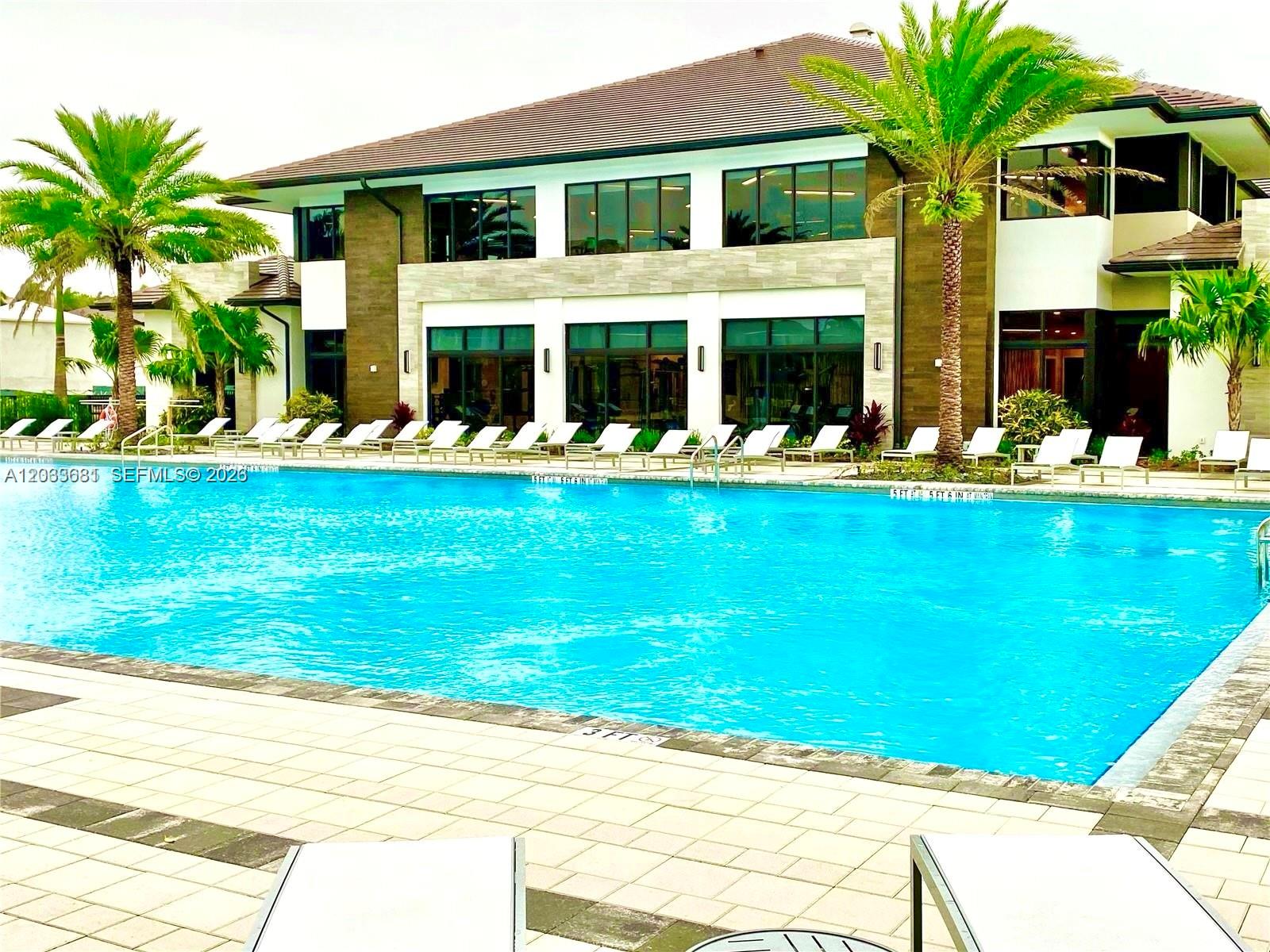 A large swimming pool sits in front of a modern two-story building with palm trees — 4700 NW 84th Ave # 15, Doral FL 33166, DORAL, FL