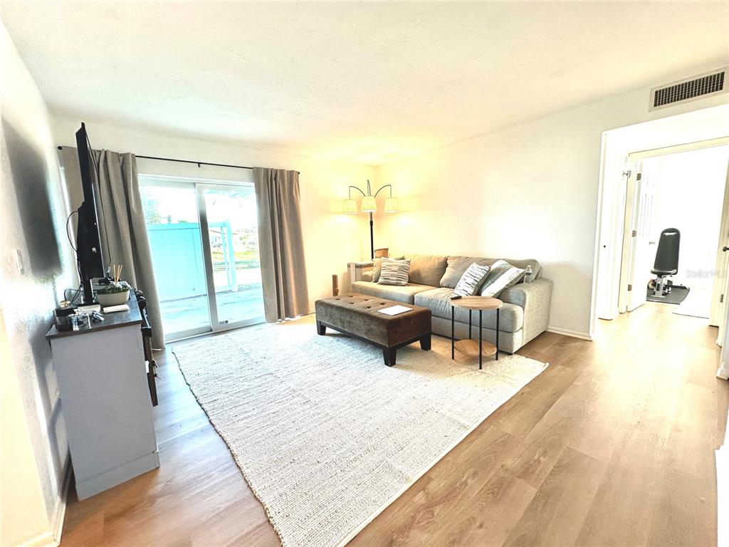 A living room features light wood flooring, a gray sofa, and a sliding glass door — 5771 GALLATIN LANE, NORTH PORT, FL
