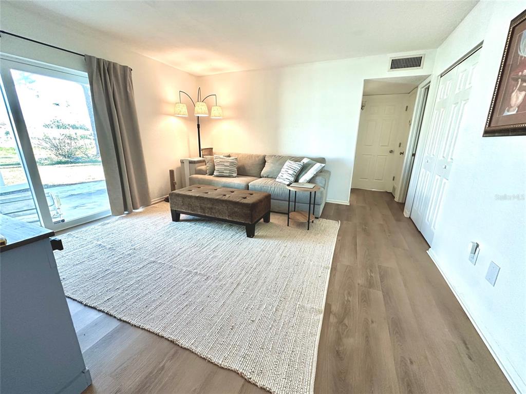 A living room features a grey sofa, a brown ottoman, and a large area rug — 5771 GALLATIN LANE, NORTH PORT, FL