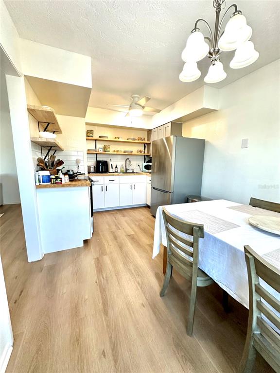 A kitchen and dining area features light wood flooring, white cabinetry, and open shelving — 5771 GALLATIN LANE, NORTH PORT, FL